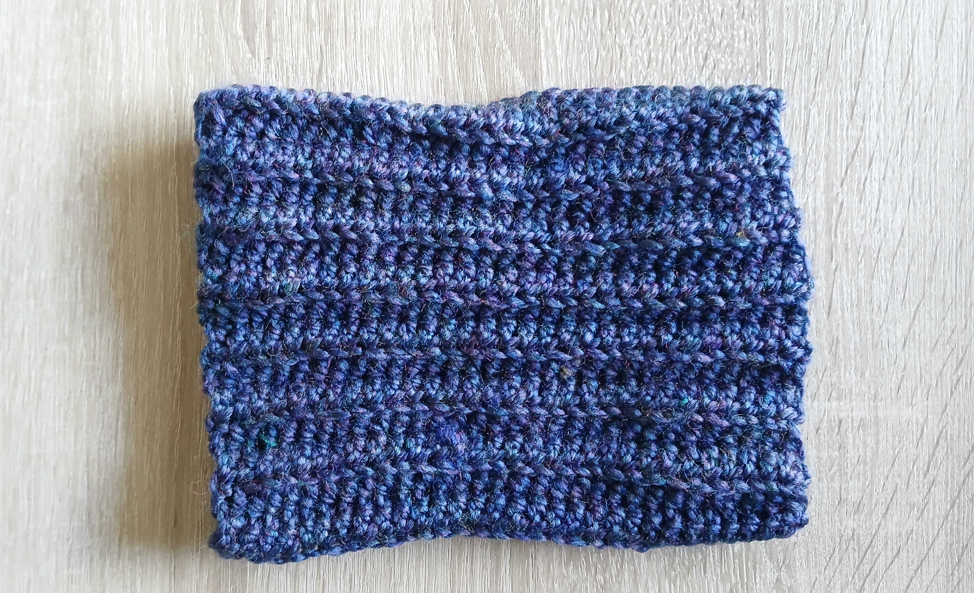 A blue dog neck warmer laying flat on a surface 