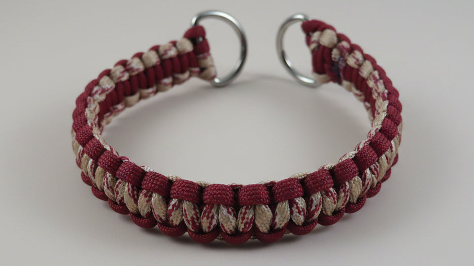 Maroon and beige braided dog collar on a wooden surface