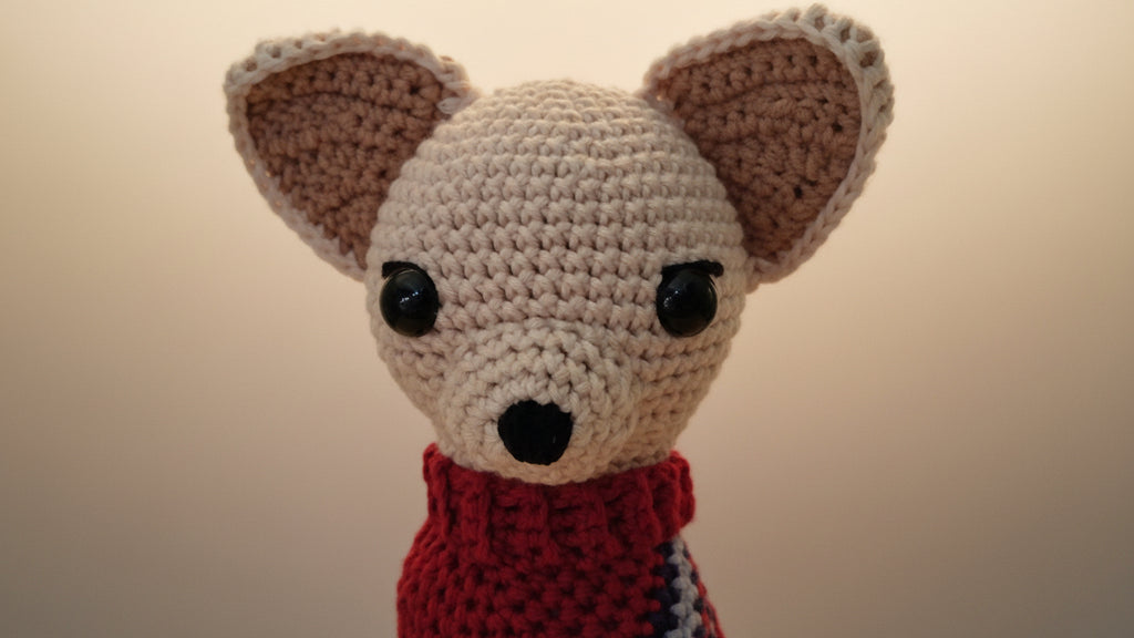 Crocheted Chihuahua toy with a red sweater on a beige background