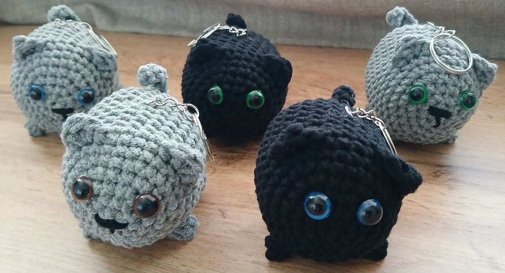 A bunch of crochet cat keychains in multiple colors