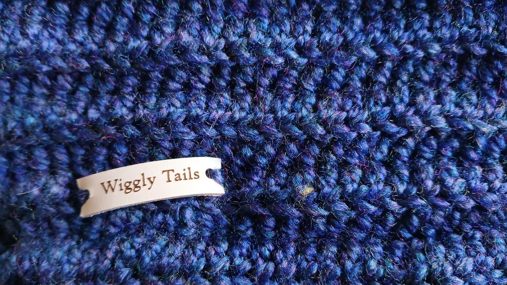 Close up of blue dog neck warmer with a leader label "Wiggly Tails"