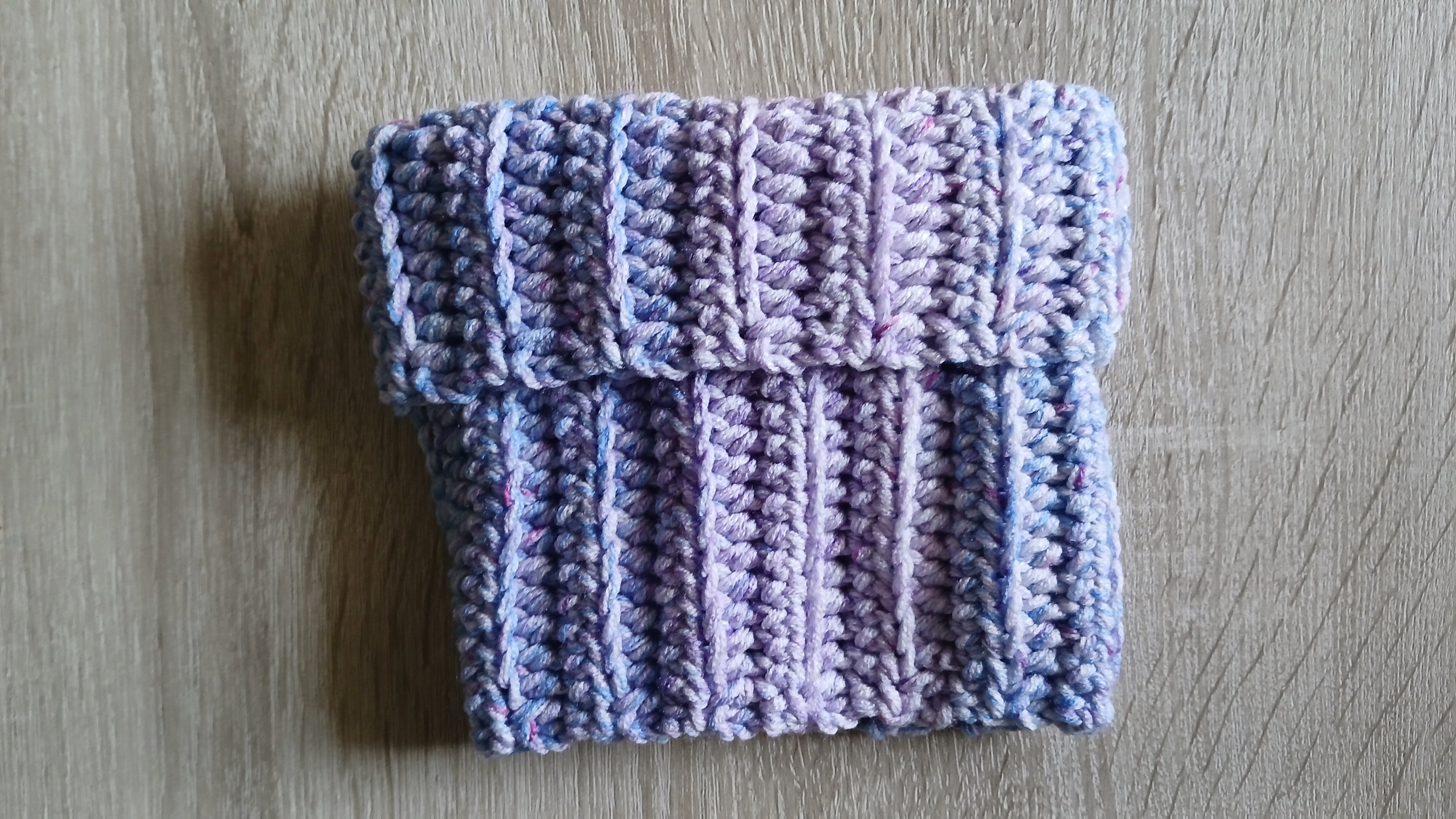 A crochet dog scarf rolled up like a turtle neck, laying on the table 