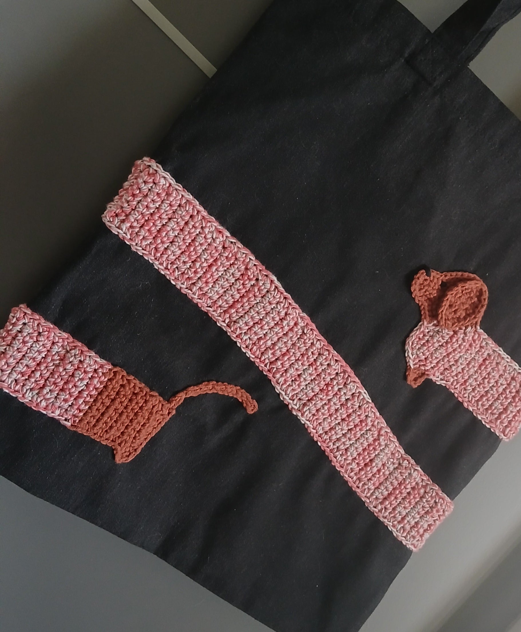 A black cotton tote bag with a dachshund applique wrapped around the bag.