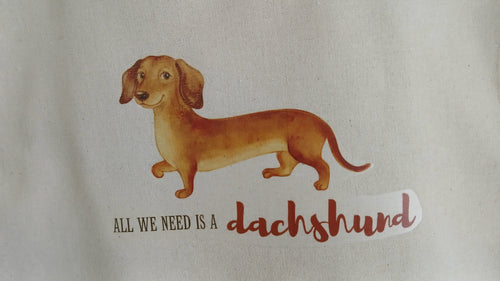 Illustration of a dachshund with text 'All we need is a dachshund' on a beige background
