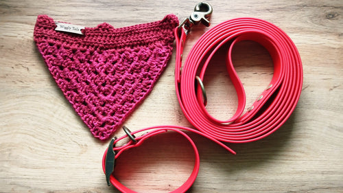 Red crochet dog bandana and matching leash and collar set on a wooden surface