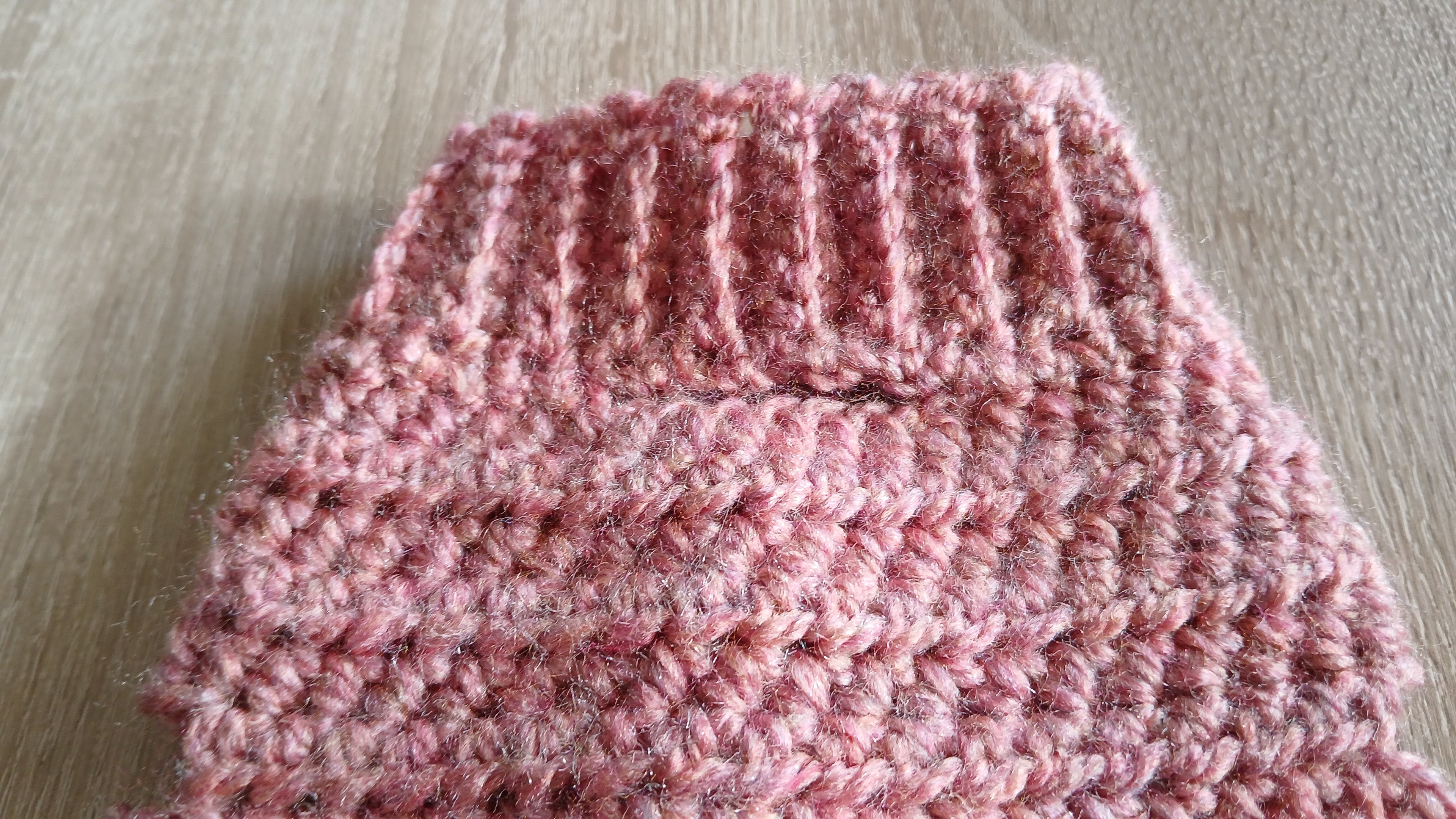 A close up of a dusty pink dog sweater, showing an opening for a leash 