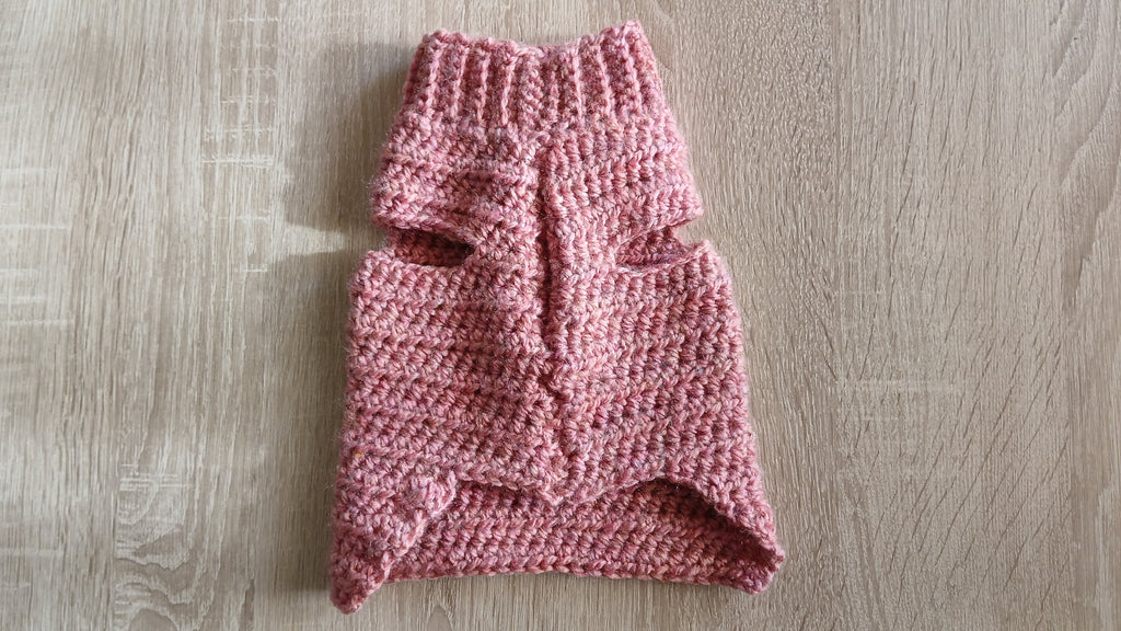 A flatlay of dusty pink dog sweater, showing sleeves 