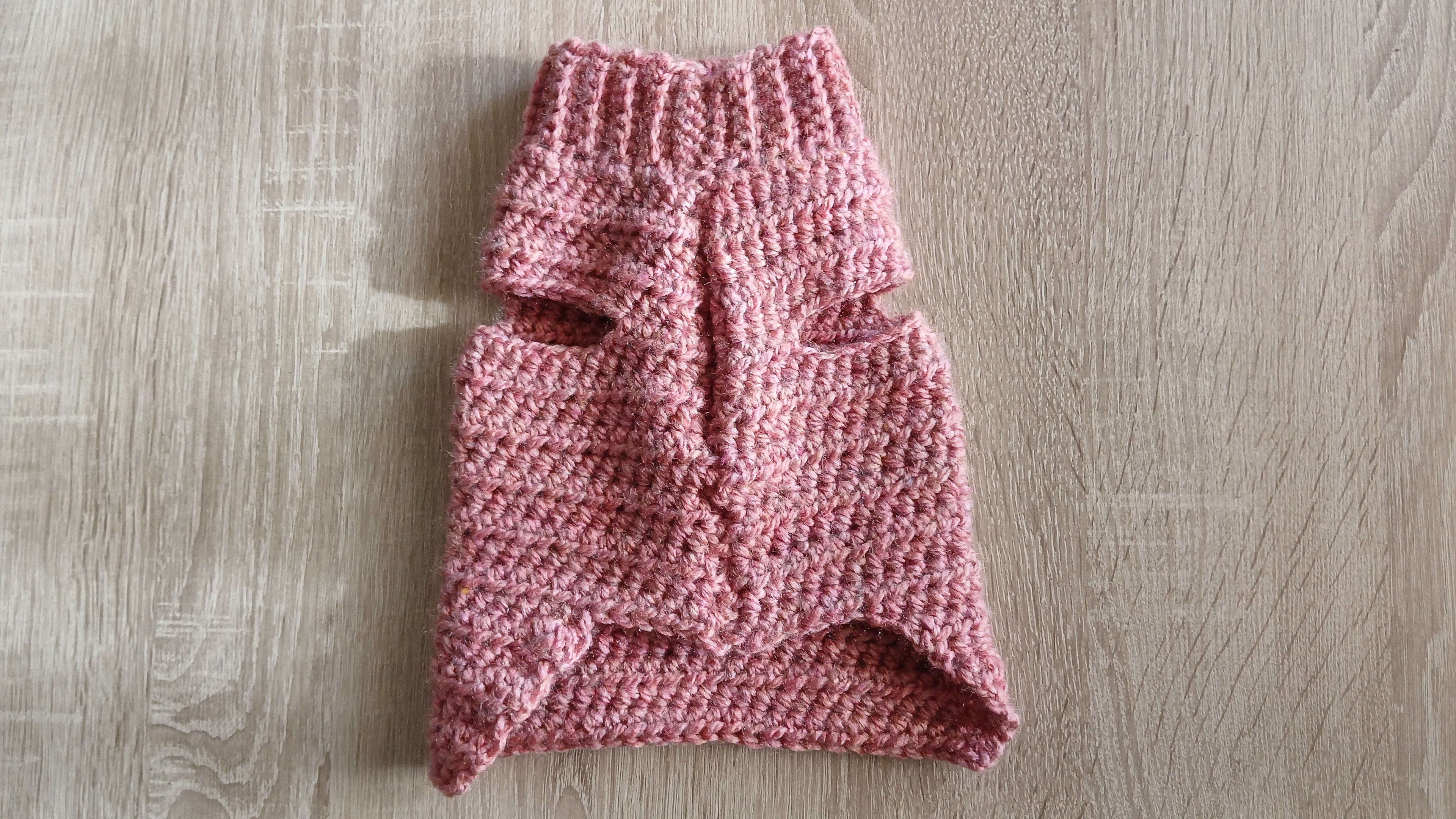 A flatlay of dusty pink dog sweater, showing sleeves 