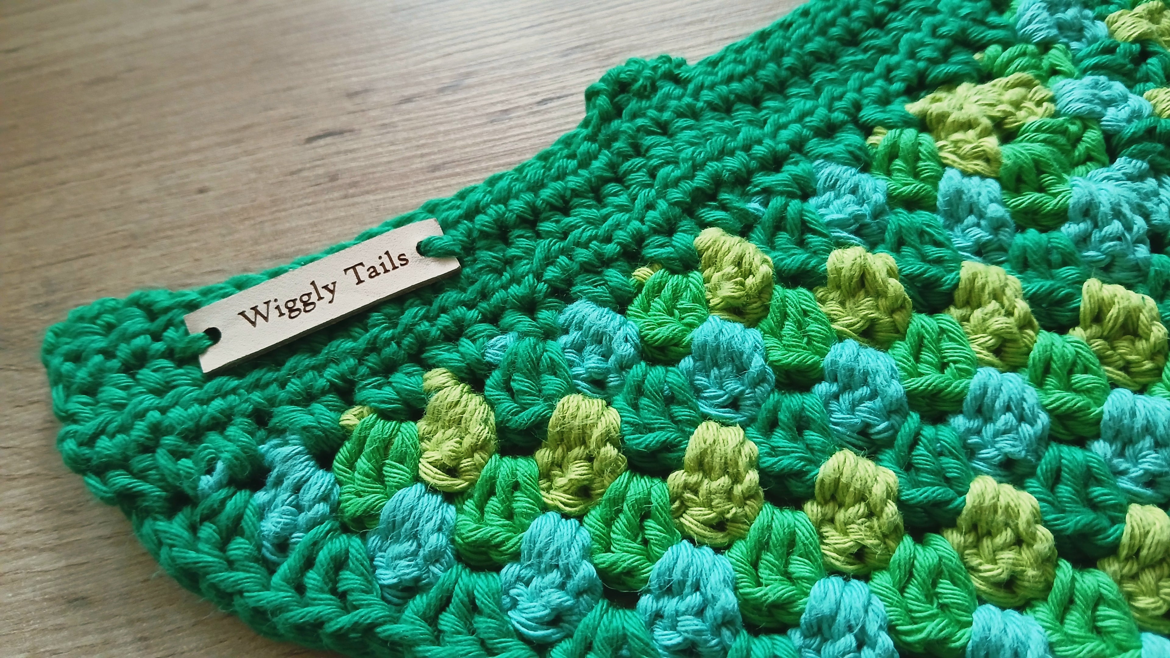 Green crochet bandana with 'Wiggly Tails' label