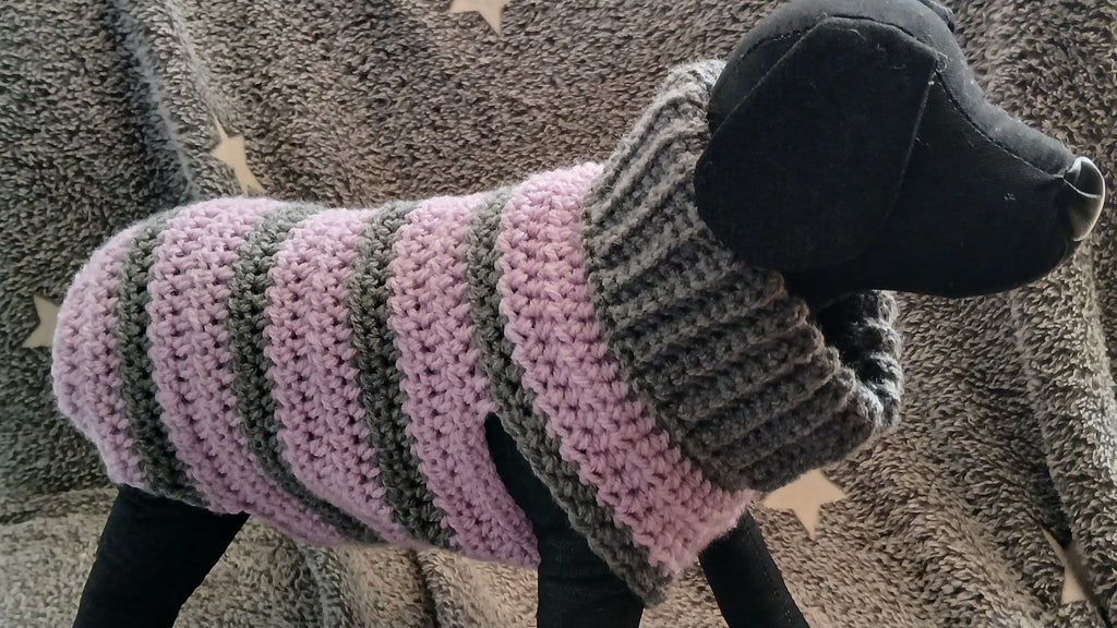 A dog mannequin wearing a striped grey - lilac dog sweater 
