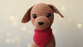 Crocheted dog toy with a red scarf on a soft focus background