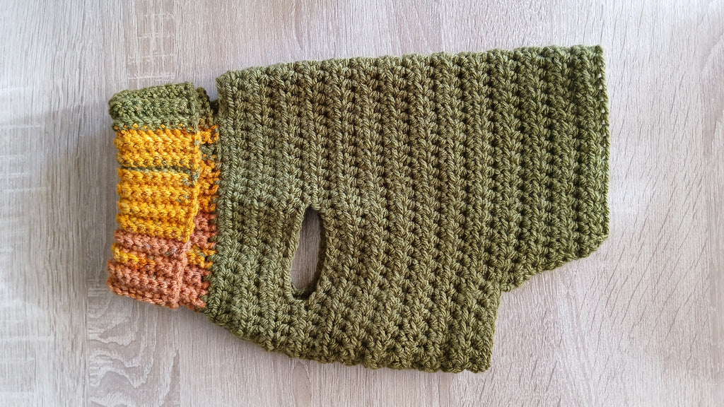 A flatlay of olive green dog sweater, showing the side