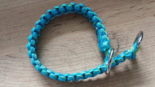 Blue braided dog collar with a metal ring on a wooden surface