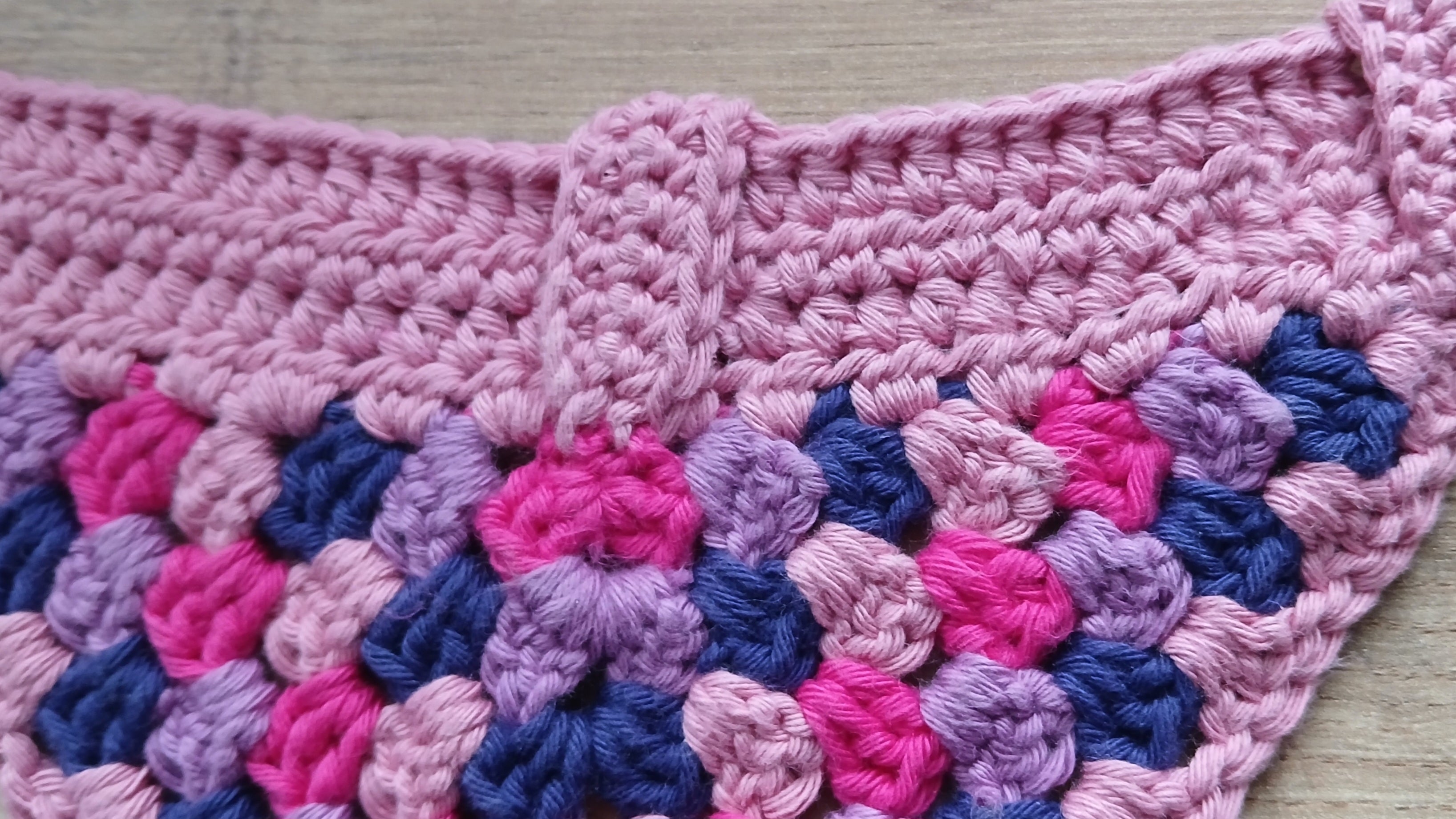 Close-up of a pink and blue crocheted fabric with a textured pattern.