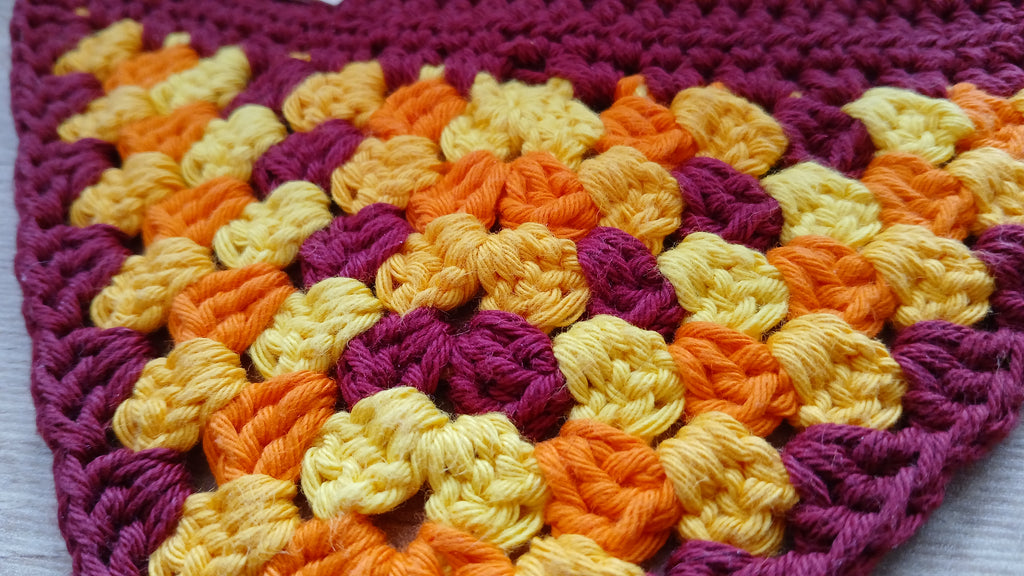 Close up of stitches of dog bandana in red, yellow and orange