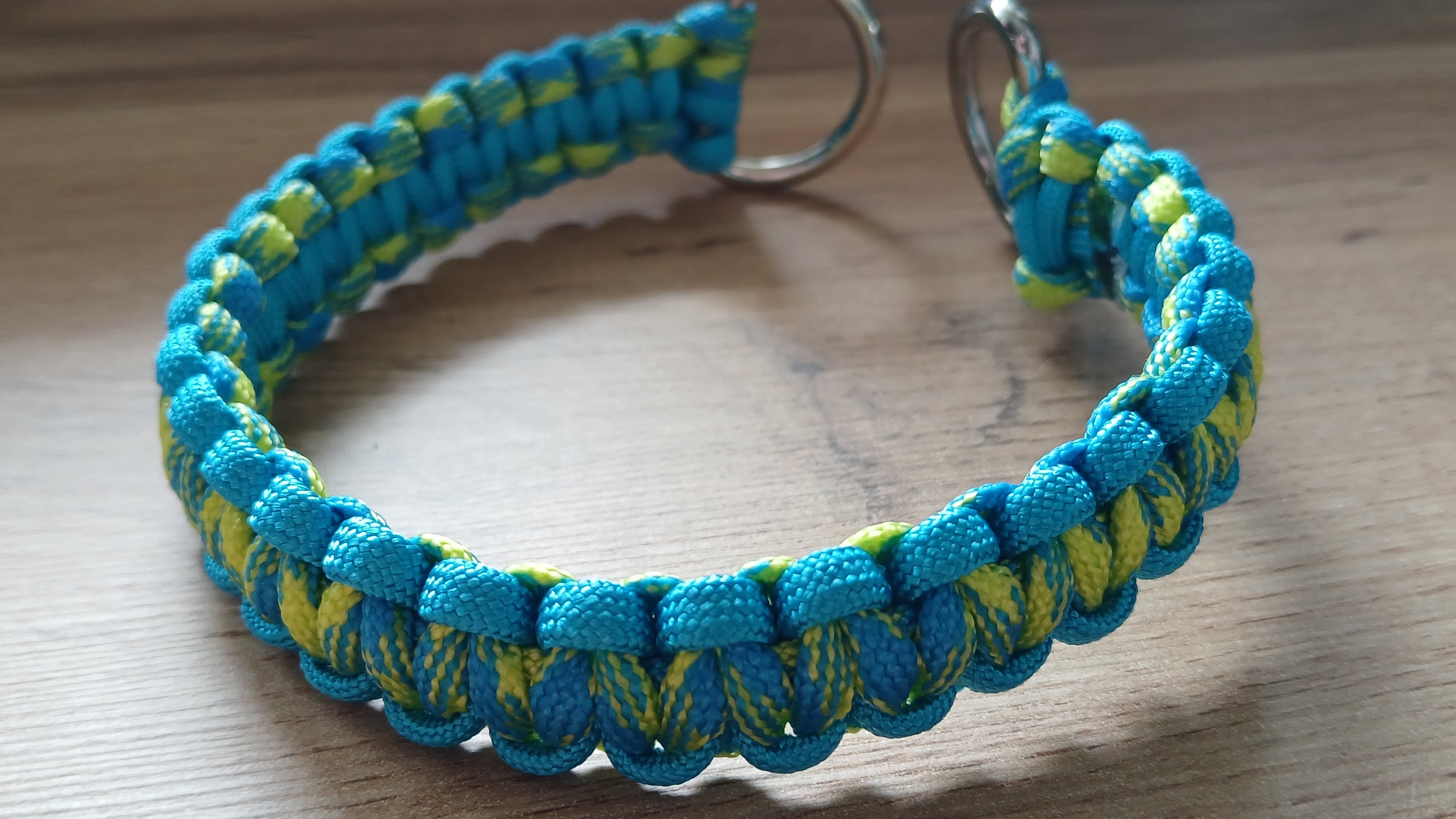 Blue and green braided dog collar on a wooden surface