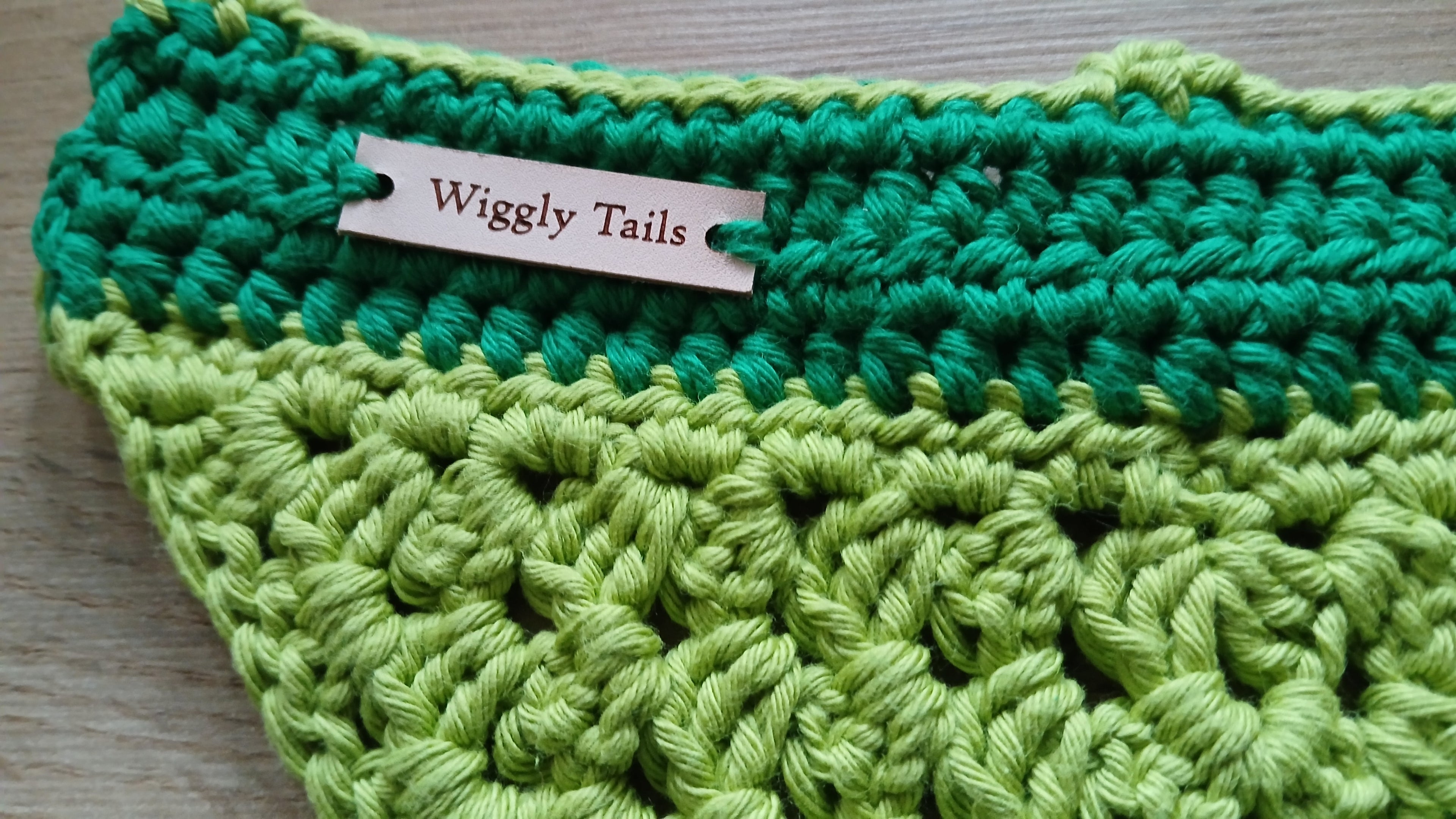 Green crocheted dog bandana with a 'Wiggly Tails' label