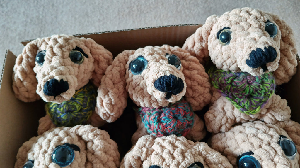 crochet dogs with colorful scarves in a cardboard box.